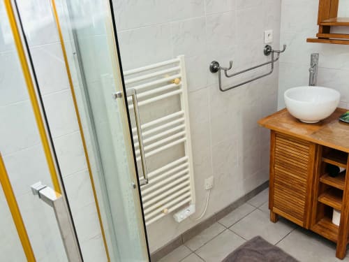 Salle de bain moderne à la Chambre Cognac du Cadran Solaire B&B avec carrelage blanc, vasque et radiateur de serviettes chauffant