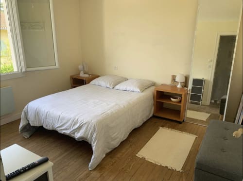 Chambre lumineuse à la Villa des Palmiers avec lit queen, tables de nuit, ventilateur et vue sur le jardin