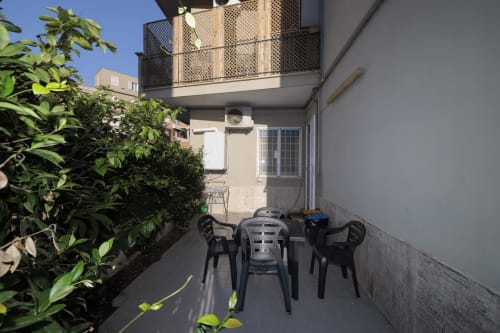 CasettAmare apartment terrace at ViOletta, Lido di Ostia with garden view, black chairs, and lush greenery