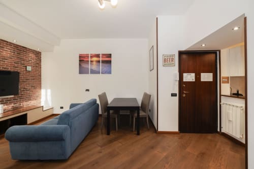 Modern living room in CasettAmare apartment at ViOletta, Lido di Ostia with blue sofa, dining table, and brick fireplace with