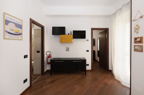 Modern living room at ViOletta apartment in Lido di Ostia with wooden floors, flat-screen TV, black furniture, and white