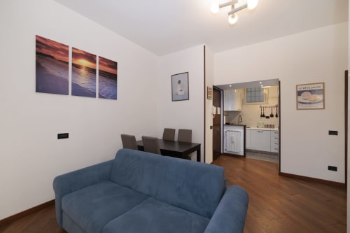 Blue sofa in CasettAmare apartment at ViOletta, Lido di Ostia, with kitchen and dining area visible
