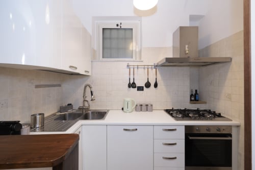 Modern kitchen in ViOletta apartment at Lido di Ostia with white cabinetry, stainless steel appliances, gas cooktop, and
