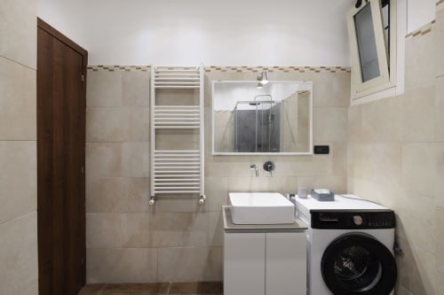 Modern bathroom in CasettAmare apartment at ViOletta, Lido di Ostia, with washing machine, sink, mirror, and heated towel