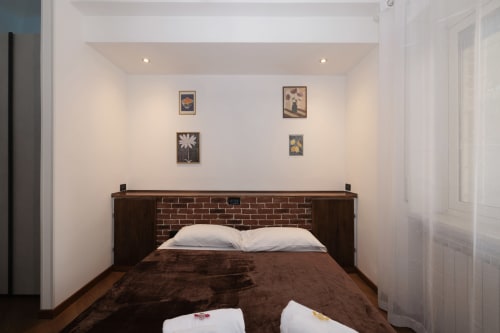 Cozy bedroom at ViOletta Lido di Ostia with brick headboard, white pillows, brown bedding, and framed wall art