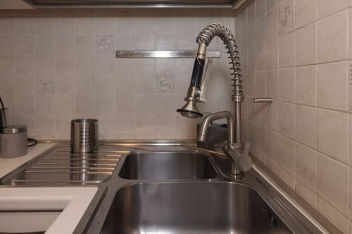 Modern kitchen sink with pull-down faucet and stainless steel counter at ViOletta apartment, Lido di Ostia