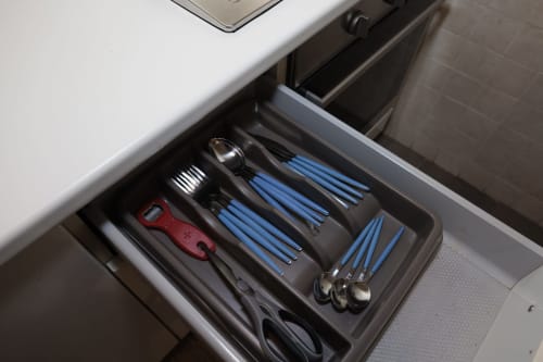 Organized kitchen drawer with cutlery, utensils, and red bottle opener at ViOletta apartment in Lido di Ostia