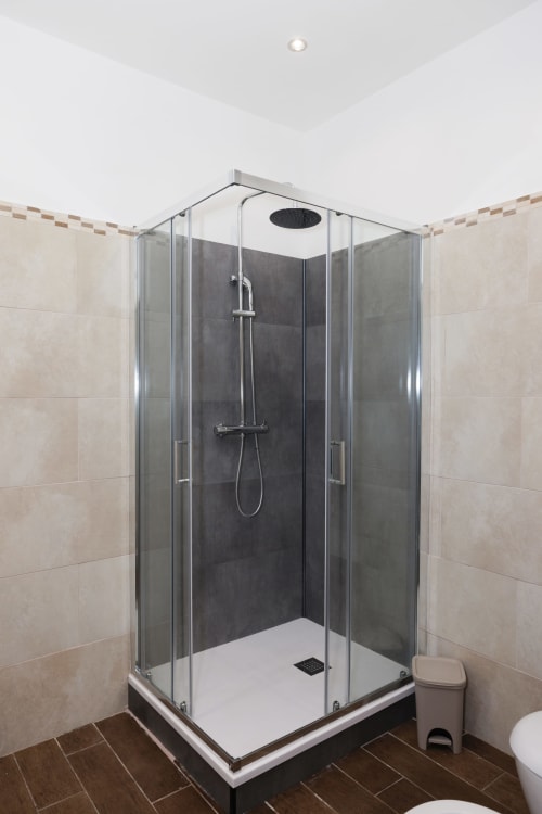 Modern glass shower enclosure in ViOletta apartment bathroom, Lido di Ostia with dark tile accents