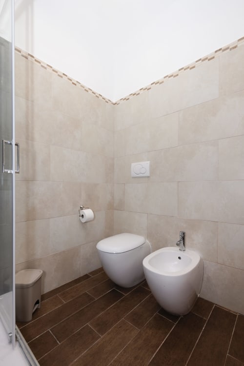 Modern bathroom in CasettAmare apartment at ViOletta, Lido di Ostia with toilet, bidet, and beige tile walls