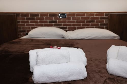 Bedroom at ViOletta CasettAmare apartment with towels on bed, brick headboard, and white pillows