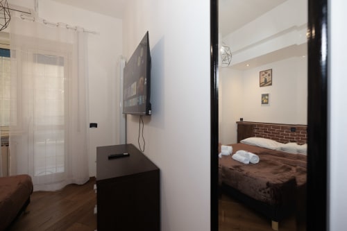 Modern apartment bedroom with flat-screen TV and ensuite at ViOletta hotel, Lido di Ostia