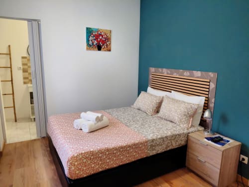 Quarto moderno do hotel Madeirarooms em Funchal com cama queen, parede em destaque azul-petróleo e vista da cidade