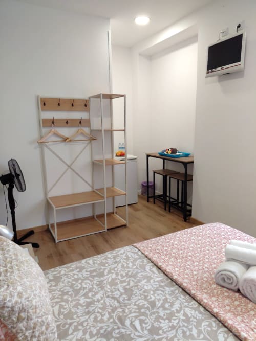 Quarto moderno do Madeirarooms Funchal com cama, prateleiras de madeira, secretária e TV na parede