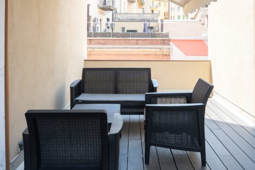 Arredamento in rete nera su terrazza in legno dell'hotel Centrale Bologna, con vista dei tetti della città sullo sfondo