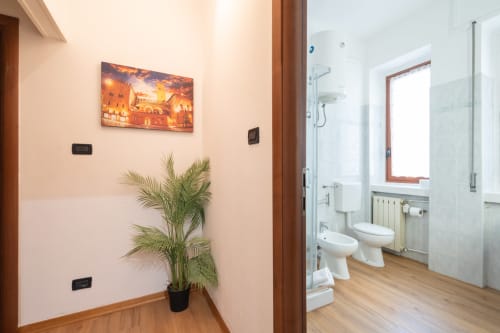Bagno moderno al Centrale Bologna con sanitari bianchi, pavimentazione in legno e finestra con vista sulla città nella camera 28