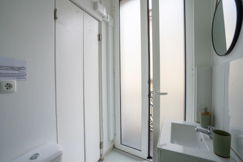 Banheiro moderno e compacto no hotel Madeirarooms em Funchal com louças brancas, espelho e box com vidro fosco