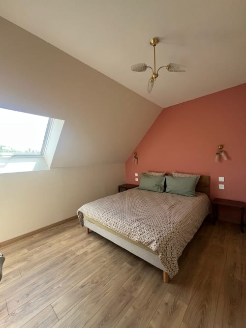 Chambre mansardée moderne au Verger en Auge avec mur terracotta, lit queen-size, lucarne et luminaire en laiton