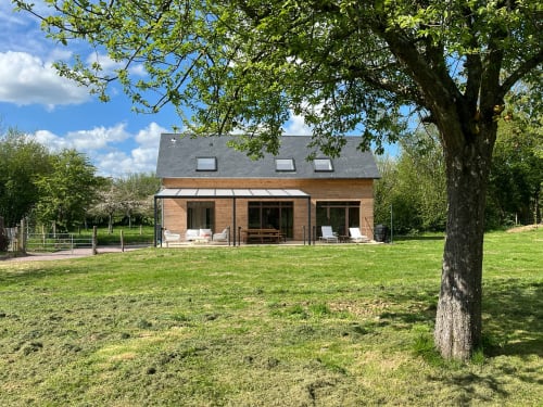 Cottage Le p'tit verger au Verger en Auge avec vue sur jardin, façade en brique, pelouse et arbre d'ombrage en Normandie