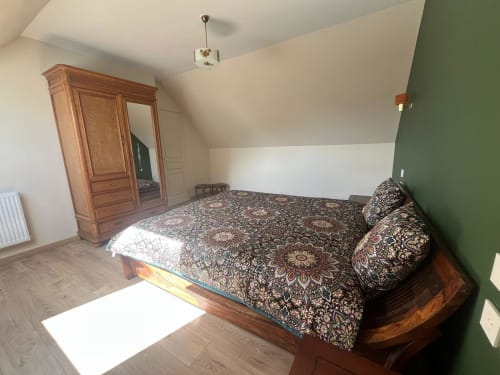Chambre douillette au gîte Le p'tit verger du Verger en Auge avec lit en bois, literie motifs, armoire et touche verte