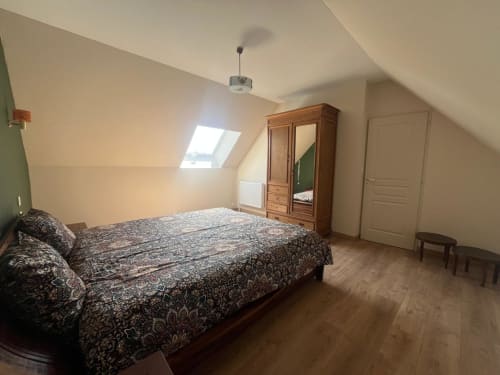 Chambre spacieuse en mezzanine au gîte Le Verger en Auge avec literie motifs, armoire bois, lucarnes et parquet