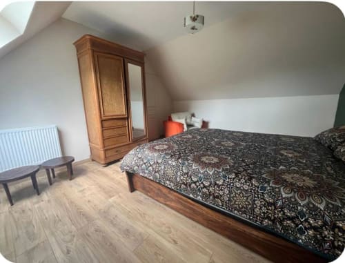 Chambre mansardée du gîte Le Verger en Auge avec lit en bois, armoire et plafond incliné à La Lande Saint Léger