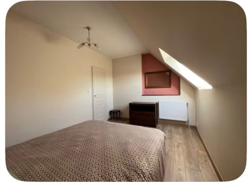 Chambre spacieuse sous les toits au gîte Le Verger en Auge avec plafond mansardé, lit queen-size, bureau et lucarne naturelle