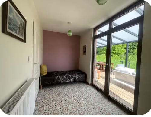 Chambre Le p'tit verger avec vue sur le jardin, portes-fenêtres et mur d'accent bordeaux au Verger en Auge