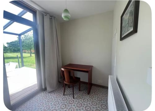 Espace de travail en cottage au Verger en Auge avec bureau, chaise, vue sur le jardin par portes vitrées et équipements modernes
