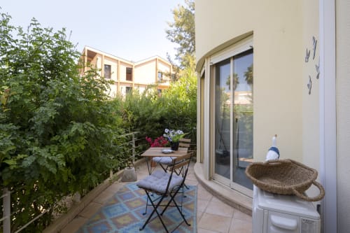 Cozy terrace at RB Algarve apartment in Vilamoura with outdoor seating, lush greenery, and glass door access