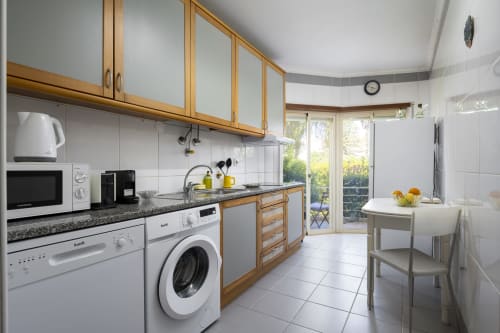 Modern kitchen in CRIS apartment at RB Algarve Vilamoura with wooden cabinets, granite countertops, and patio view