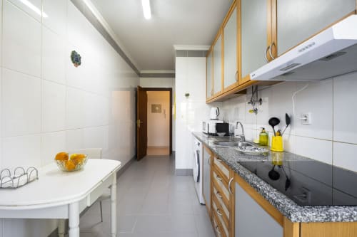 Modern kitchen in CRIS Vilamoura apartment with granite counters, wooden cabinets, white tiles, and full appliances at RB