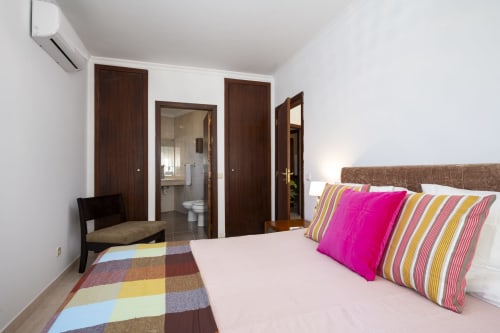 Bright modern bedroom at RB Algarve Vilamoura with colorful pillows, wooden doors, and contemporary furnishings