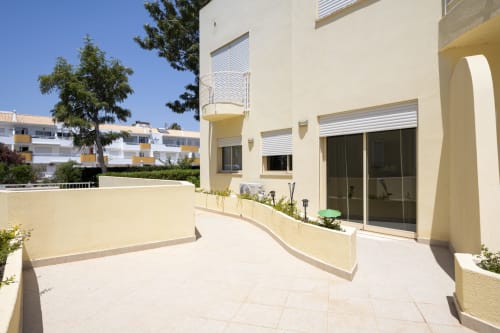 Spacious terrace at RB Algarve apartment in Vilamoura, PT with cream-colored walls, modern sliding doors, and lounging area