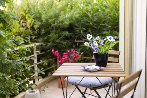 Terrace seating at RB Algarve with potted flowers, lush garden, wooden table and chair with water view