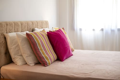 Cozy bedroom at RB Algarve Vilamoura apartment with beige headboard, cream pillows, and colorful striped and magenta