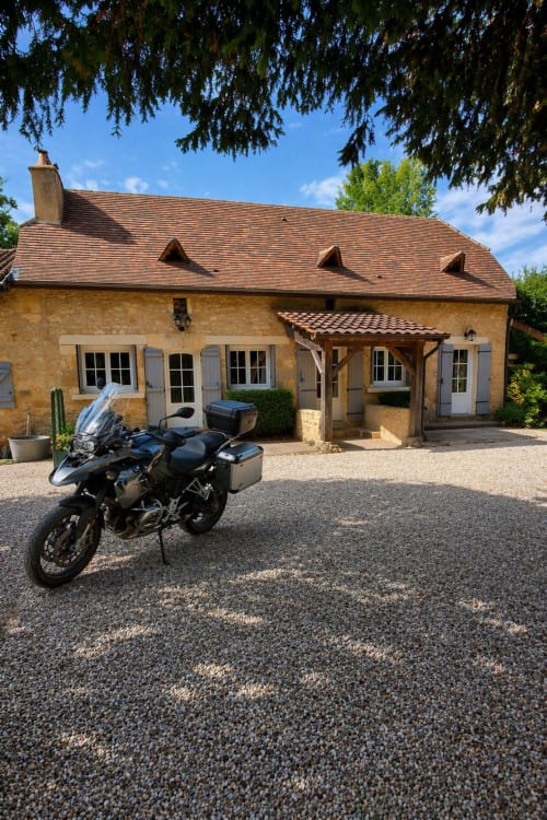 Moto d'aventure garée aux Gîtes Le Pech, gîte en pierre à Sainte-Foy-de-Longas, France