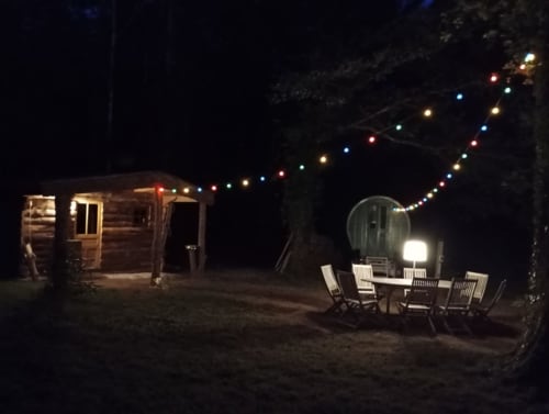 Vue nocturne du gîte Le Campement aux Tramois B&B à Donzy, France, avec guirlandes lumineuses colorées et espace extérieur