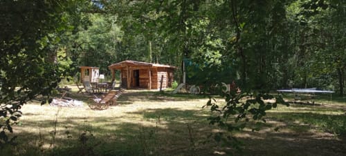 Wooden cottage accommodation at Les Tramois guesthouse in Donzy, France, surrounded by trees and garden