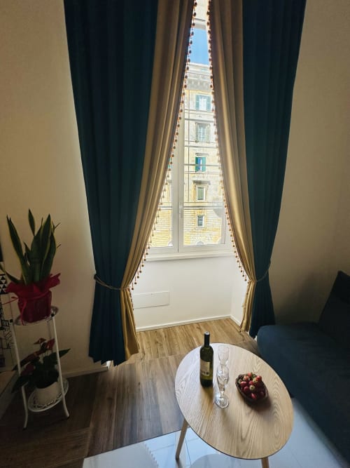 Camera deluxe presso St Mary Major Loft a Roma con vista sulla città, tavolo rotondo con vino, tende eleganti e pavimento in legno
