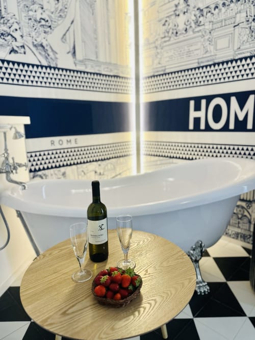 Elegante bagno dello St Mary Major Loft Roma con vino, flute di champagne e fragole su tavolo tondo davanti alla vasca