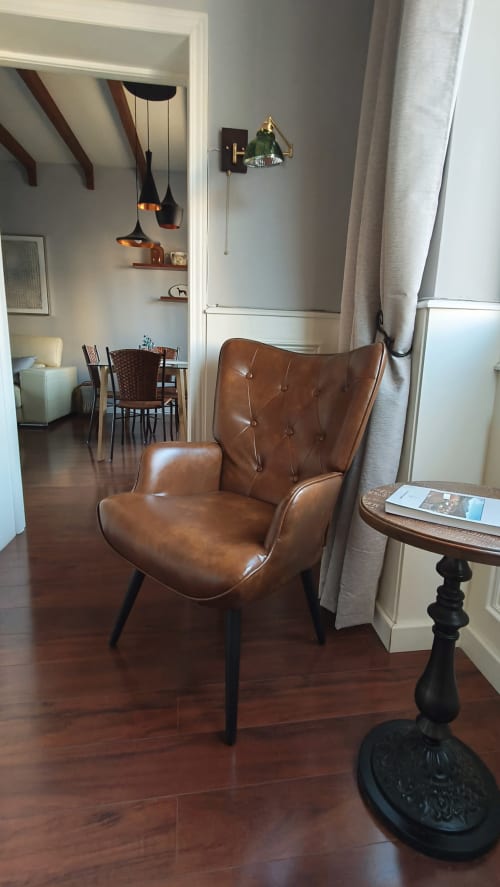Sillón orejero de cuero marrón en habitación moderna del hotel Mirador Medieval en Cáceres, con suelos de madera y decoración contemporánea