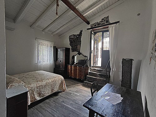 Camera rustica presso Il Tanaceto B&B in Sicilia con letto, mobili in legno, travi a vista e porte che si affacciano sul giardino