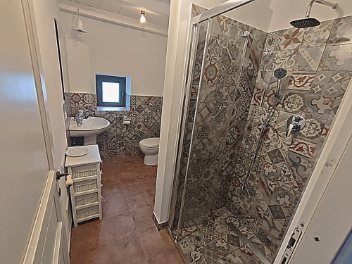 Bagno moderno all'Il Tanaceto B&B a Castiglione di Sicilia con doccia in piastrelle ornate, lavabo a colonna e pavimento rustico