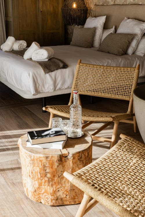 Lujoso dormitorio en Mas Escarrà con silla tejida, mesita de madera y elegante ropa de cama blanca en Caldes de Malavella