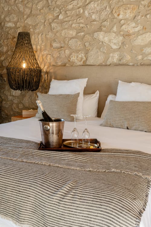 Lujosa habitación del hotel Mas Escarrà en Caldes de Malavella con pared de piedra, champaña y ropa de cama a rayas