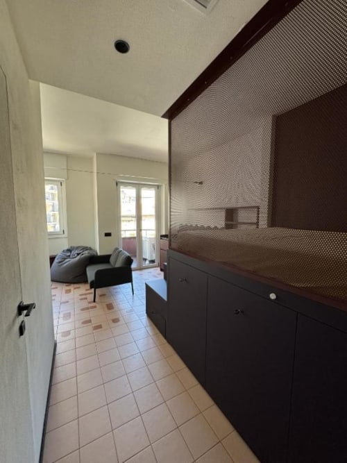 Corridoio moderno dell'appartamento studio Muratori Apartments Milano, con mobili scuri, pavimento piastrellato e vista sul living