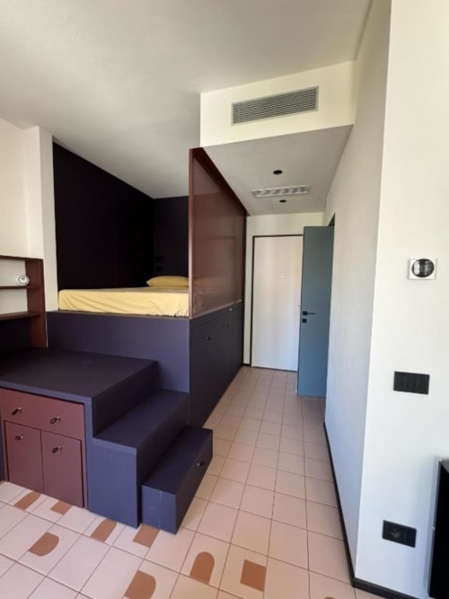 Monolocale moderno a Muratori Apartments Milano con letto rialzato, soluzioni di stoccaggio integrate e pavimentazione in cotto