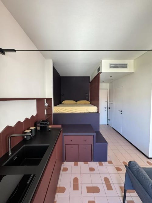 Monolocale moderno presso Muratori Apartments Milano con cucina, letto rialzato e piastrelle geometriche