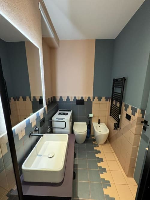 Bagno moderno con doppio lavabo, wc, bidet e piastrelle geometriche presso Muratori Apartments Milano