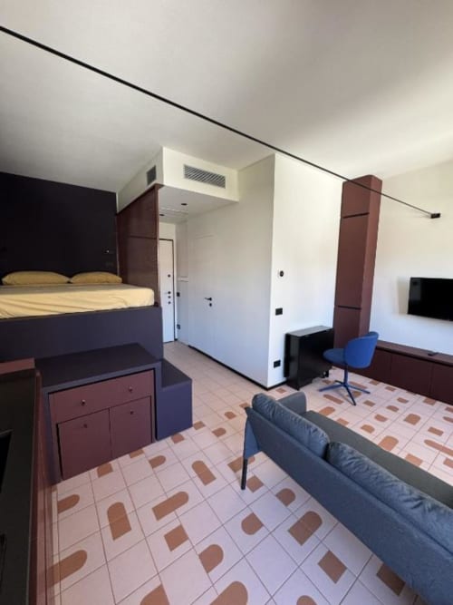 Monolocale a Muratori Apartments Milano con letto, divano, scrivania e pavimento in piastrelle decorative